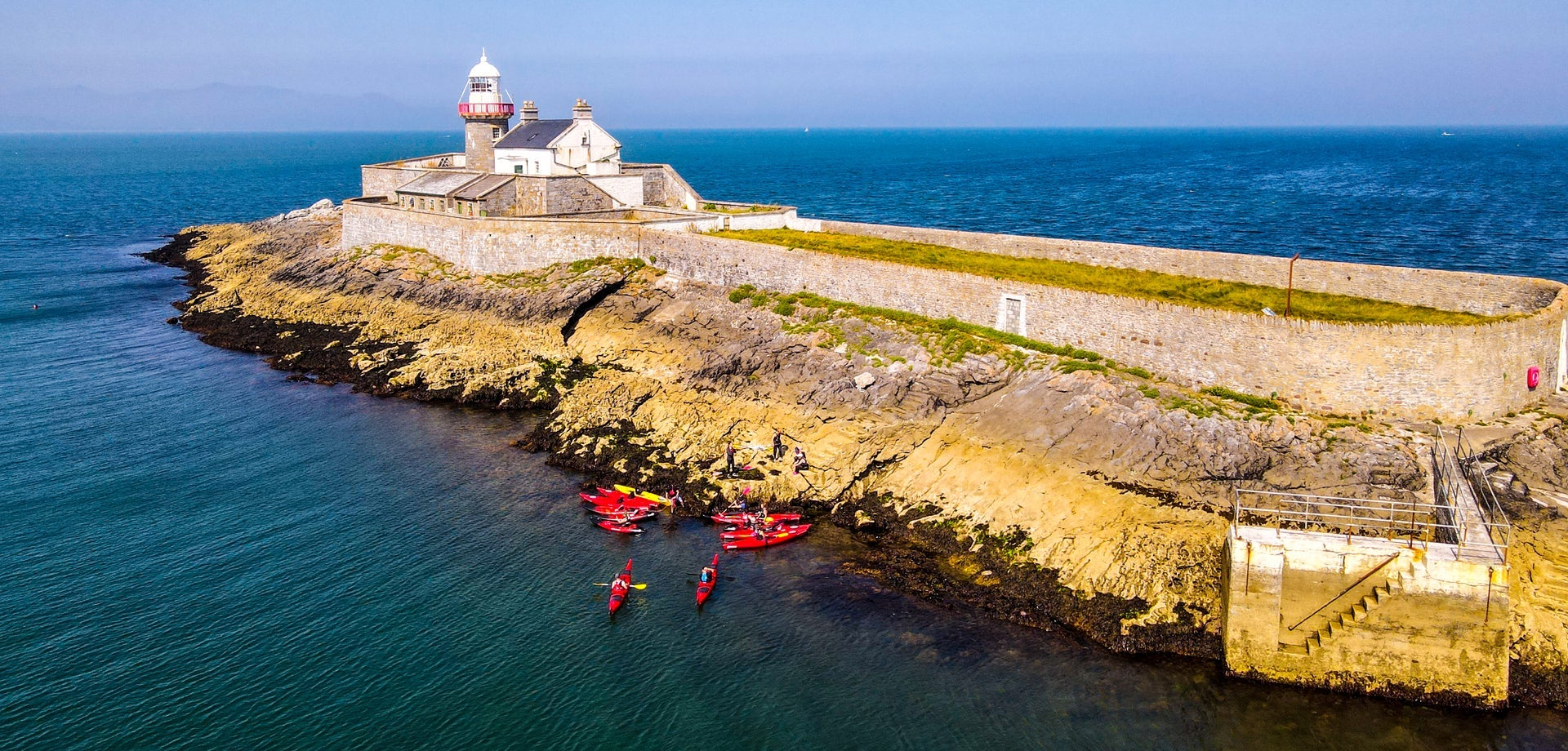 Aerial view of a group of kayakers near a lighthouse