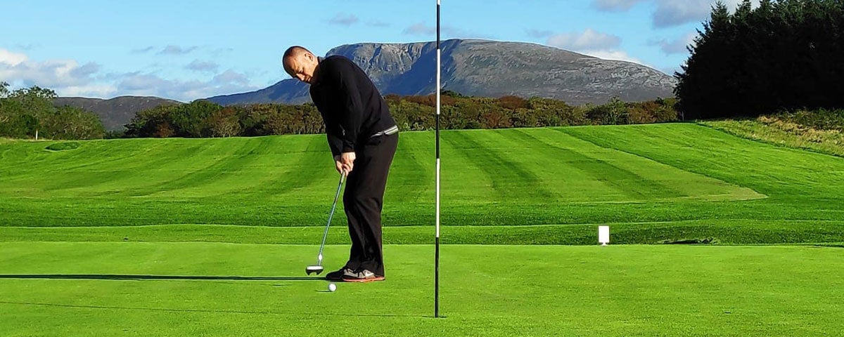 Cloughaneely Golf Club with person putting on a green and Muckish Mountain in the background