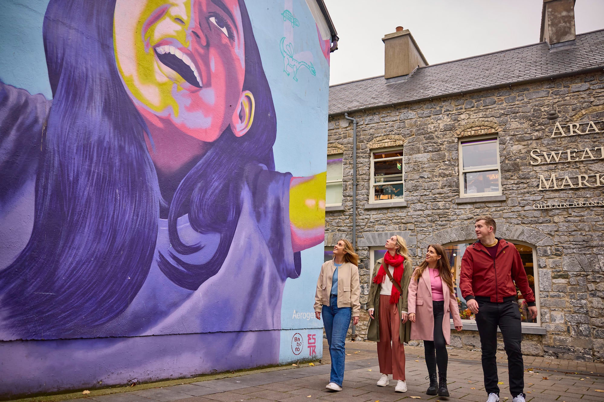 People walking past a mural in Galway city