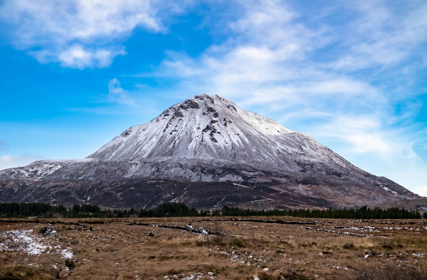A mountain with a pale coloured peak and dark bogland at the foot