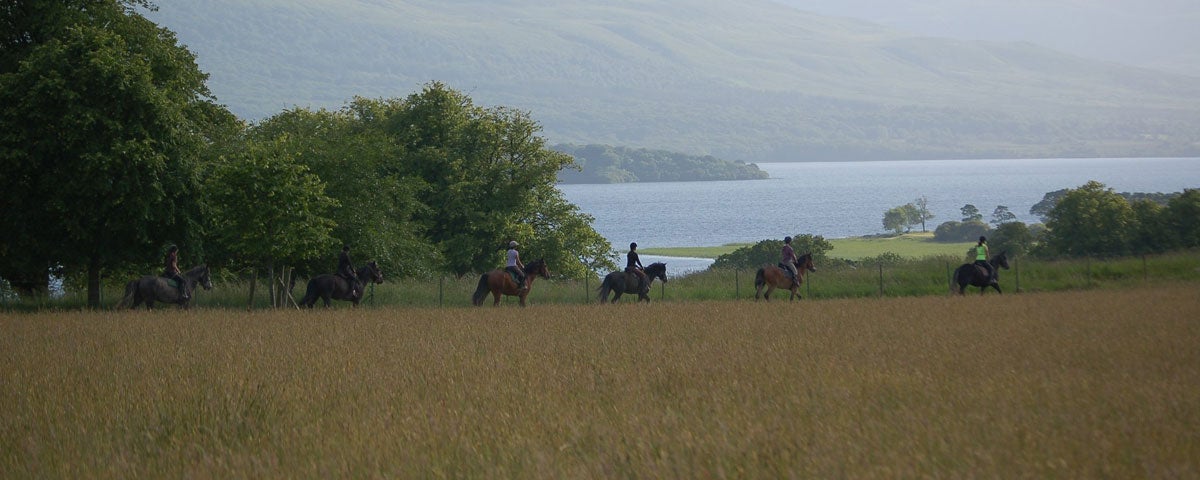 A group of people on horseback with a view of a lake and mountains in background