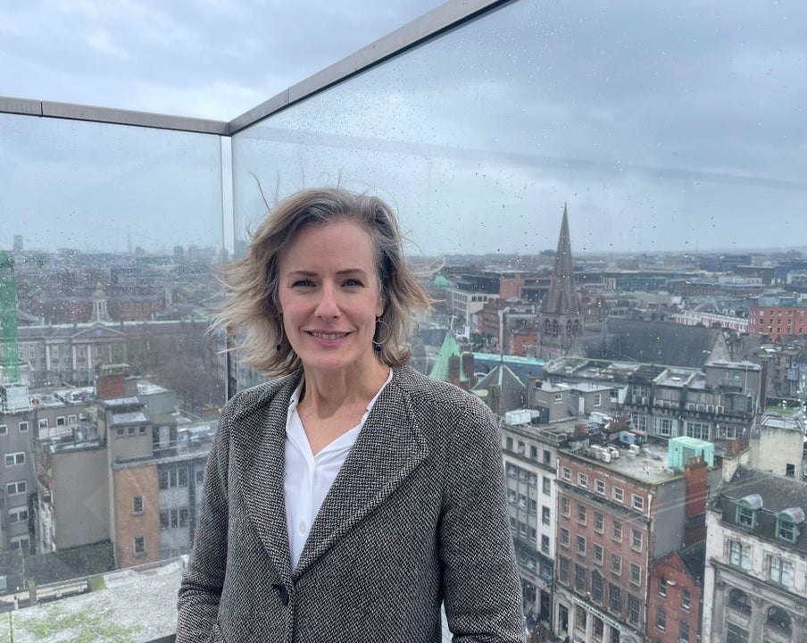 A lady standing on a balcony with a view out over Dublin as the back drop