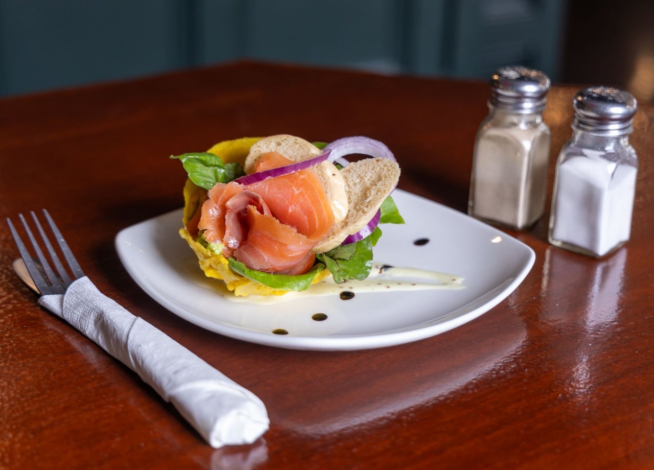 Smoked salmon served with bread and garnishes on a white plate with cutlery and condiments