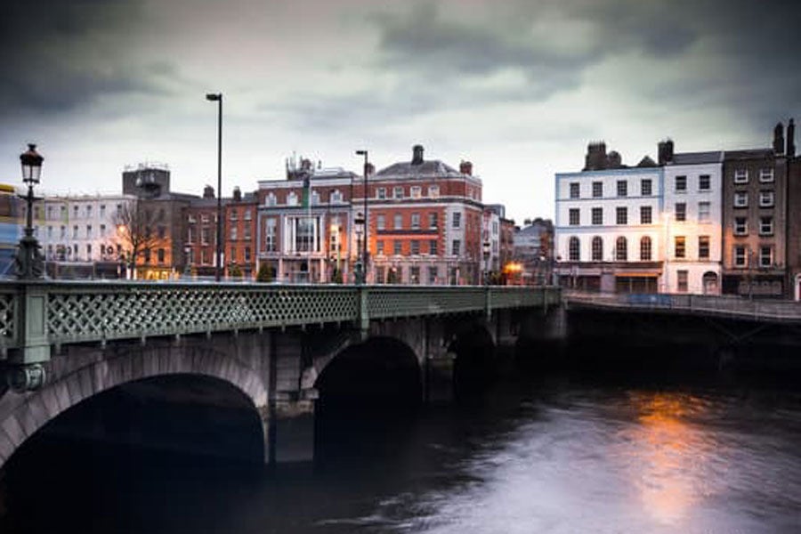A evening view of a buildings overlooking a river beside a bridge