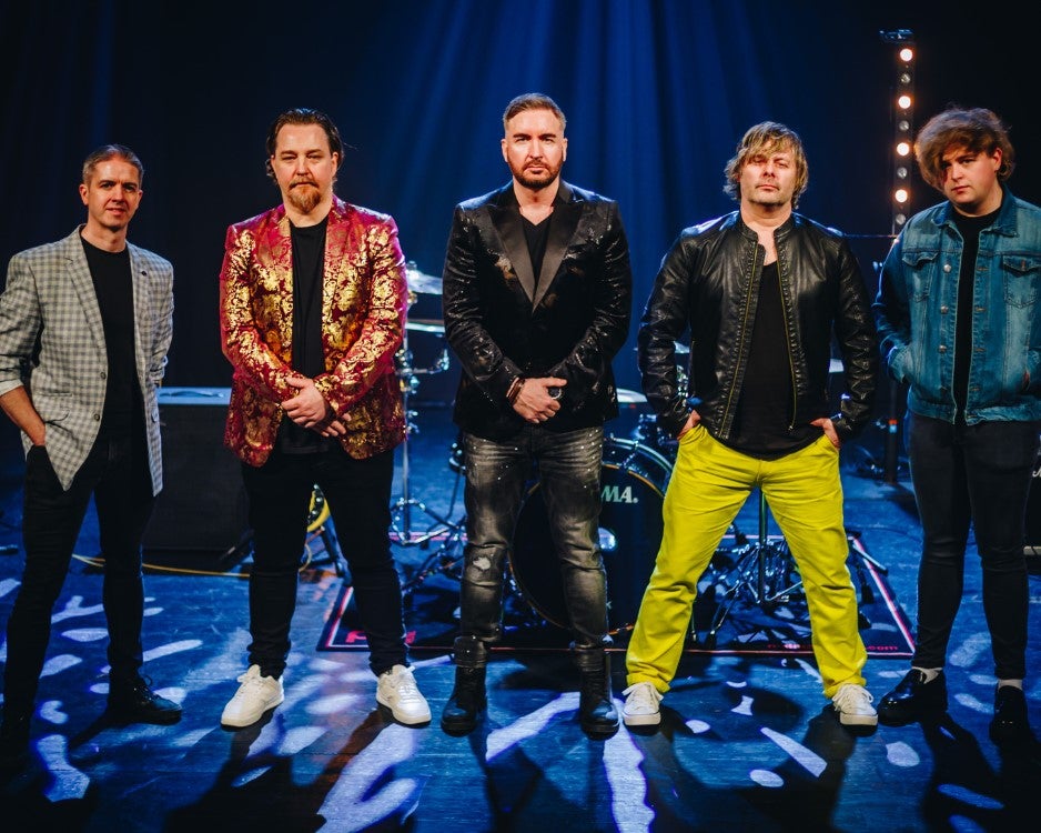 A line of 5 men in bright or shiny black jacket on the front of a stage.