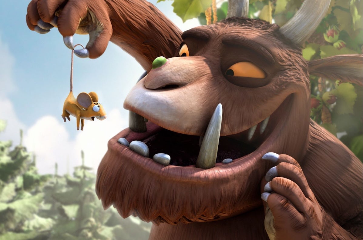 A large brown animal with tusks is holding up a tiny shocked mouse in front of his face