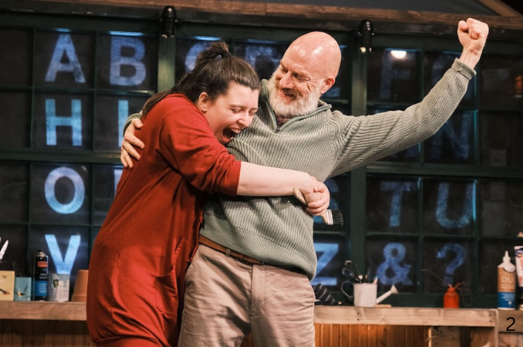 A joyful woman is hugging a smiling man who is holding a fist up in the air