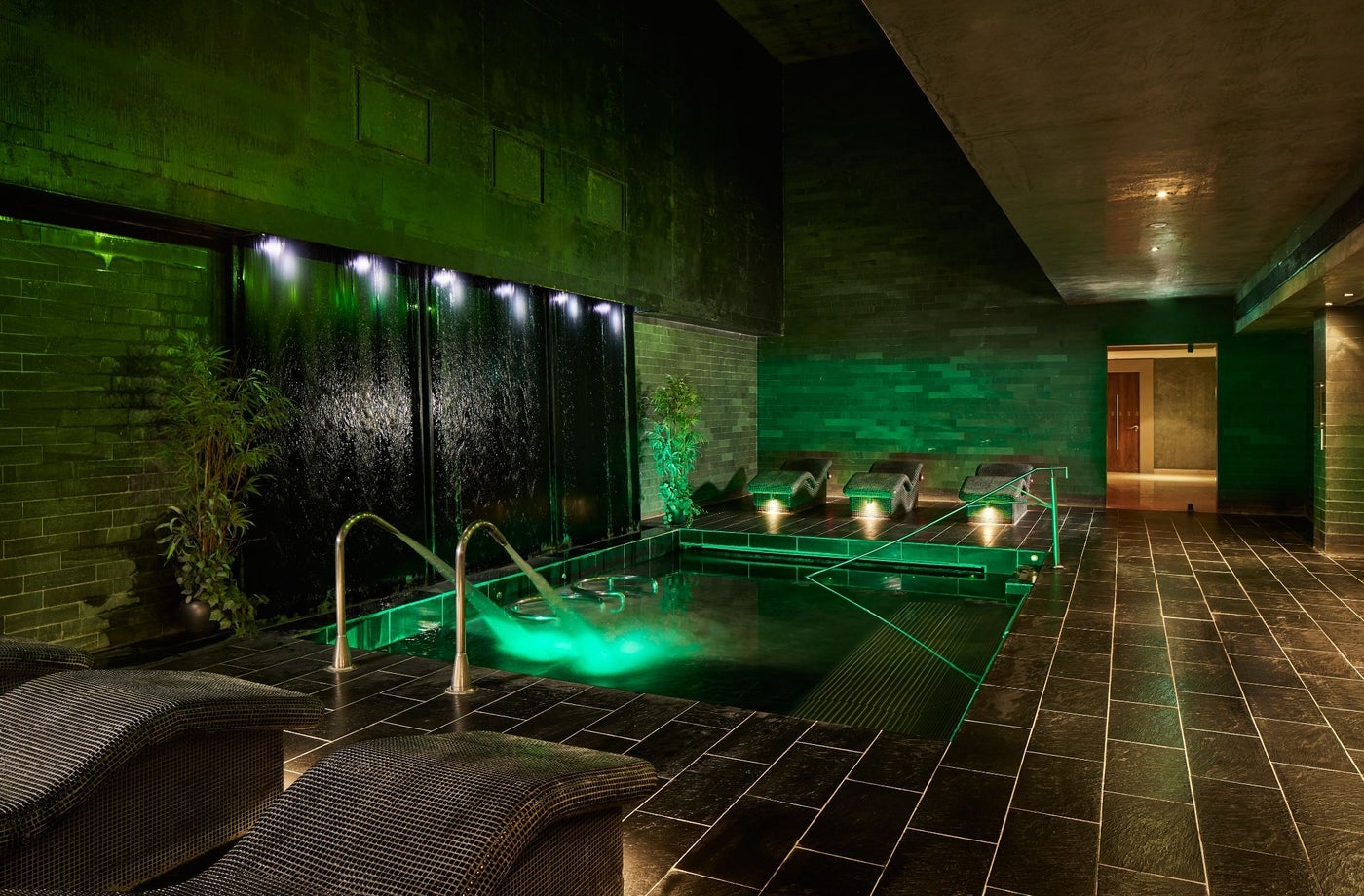 A wall to floor tiled room with a small pool