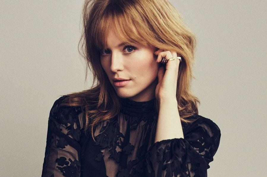 A woman touching her left ear, looking at the camera
