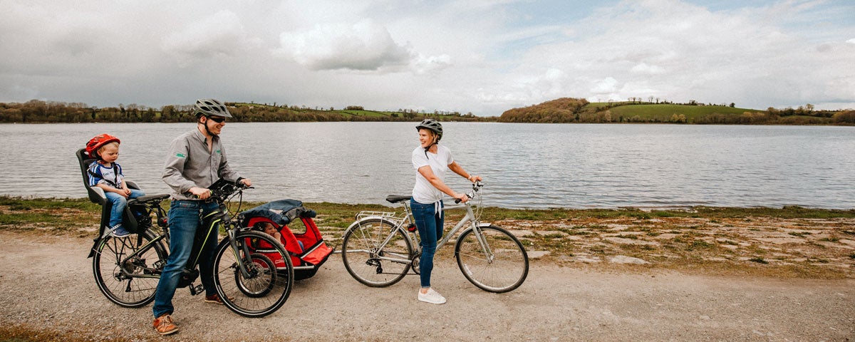 Couple with two children on bikes beside a lake