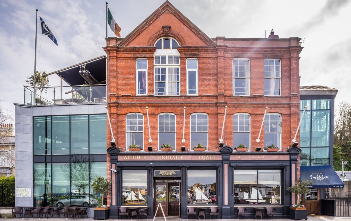 The exterior of a red brick building with glass extension and roof terrace