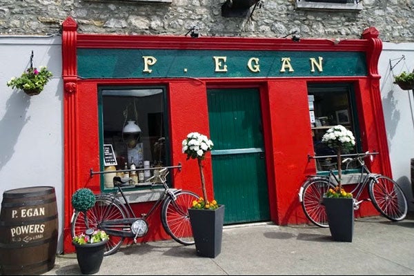 Exterior of P Egan Bar with red shopfront and bicycles and potted plants outside