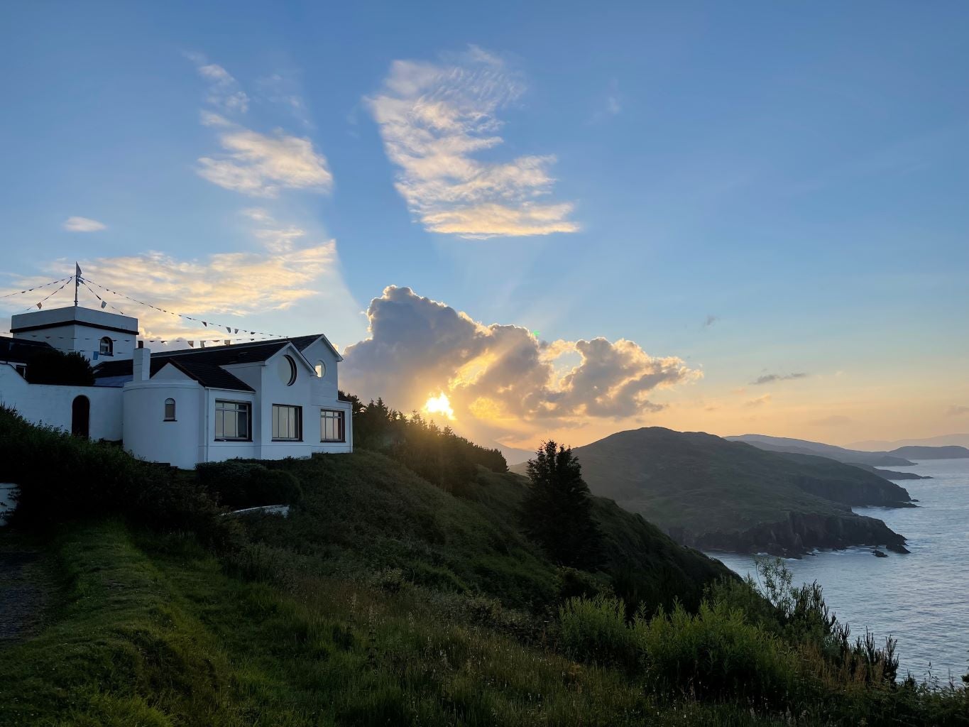 A white building on a hill near the sea.