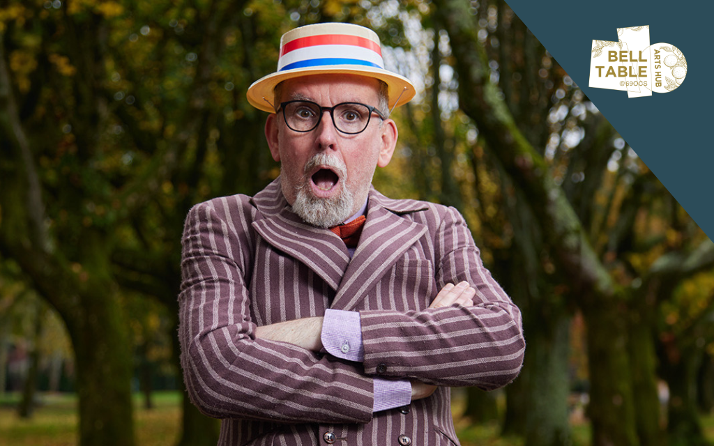 A man wearing a straw boater hat is looking shocked with mouth wide open and arms crossed in stripy blazer.