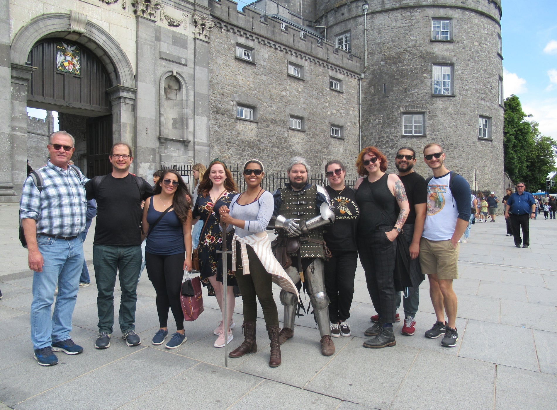 Tour group posing outside a castle with their tour guide dressed as a knight