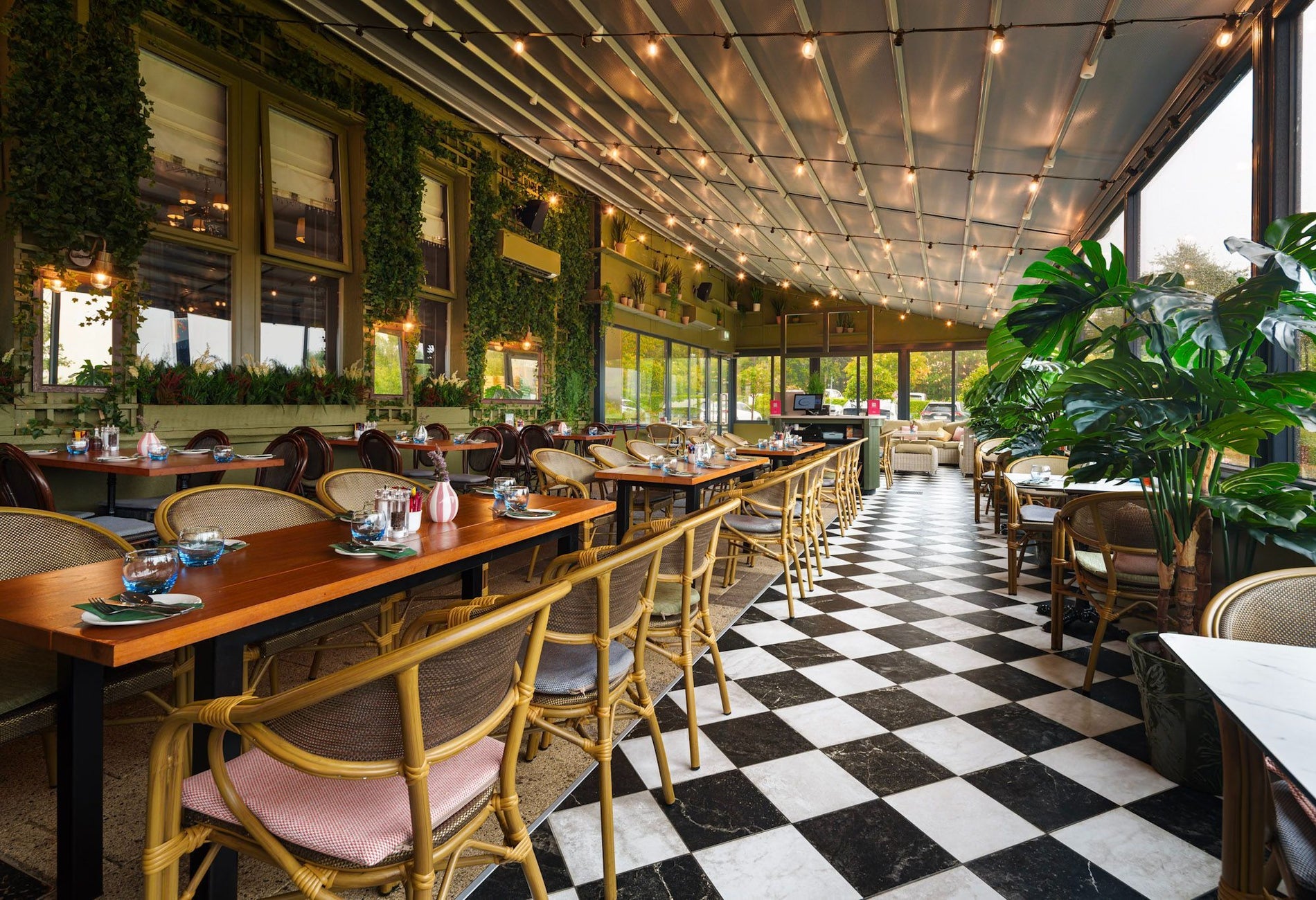 Three rows of tables set for service with chairs and a black and white tiled floor