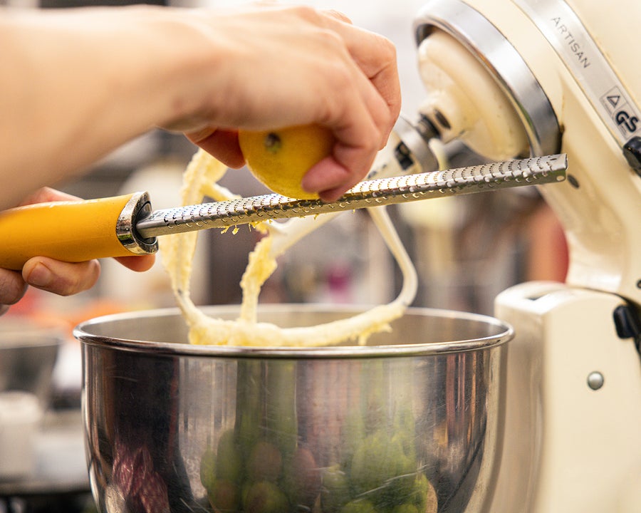 Christmas Cakes & Sweet Treats. A pair of hands grating a lemon into a large mixer bowl.