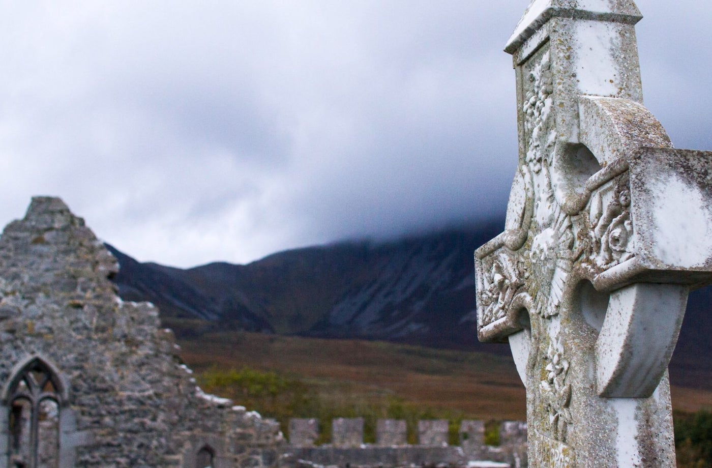 Close up image of a celtic cross and a church ruin