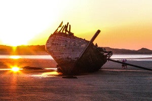 image of boat wreckage with sunset.