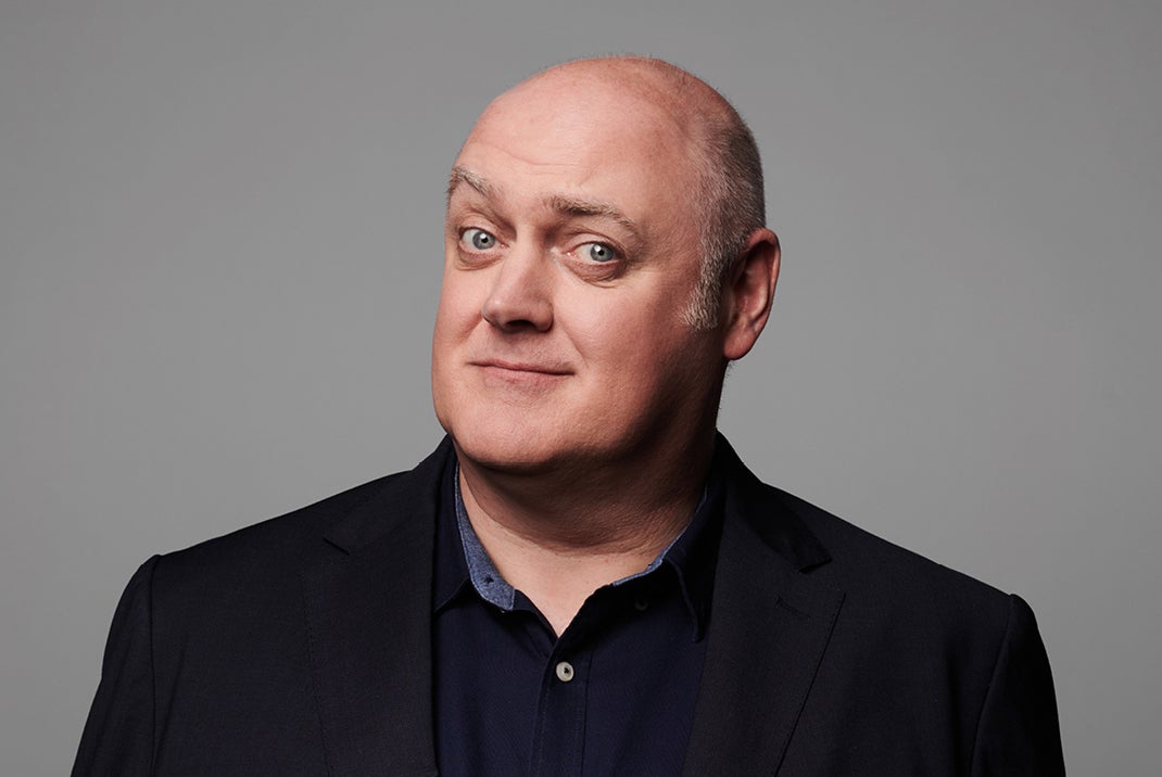 A man with quizzical smile in dark shirt and jacket.