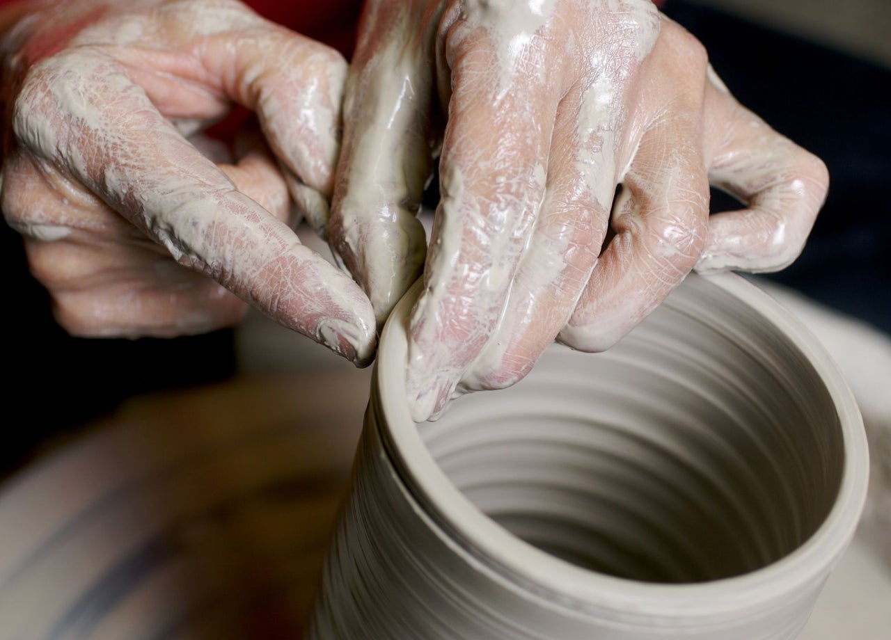 Hands shaping clay on a pottery wheel
