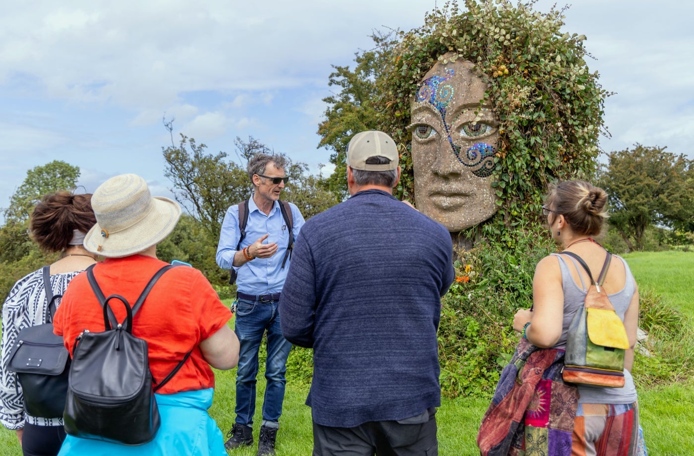 People and a tour guide in a field at a stone monument