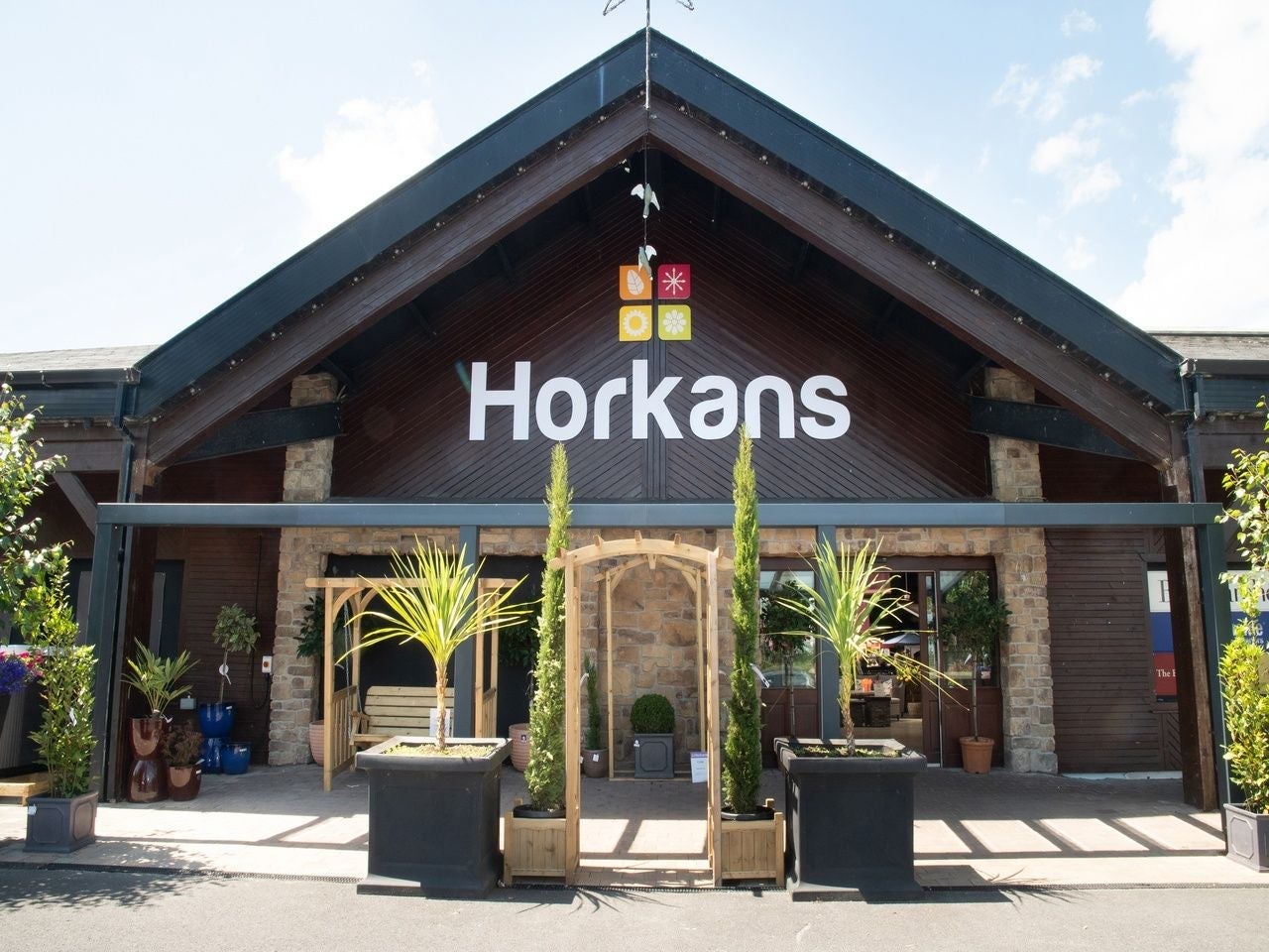 Front entrance of a business with wooden façade stone pillars and potted plants outside