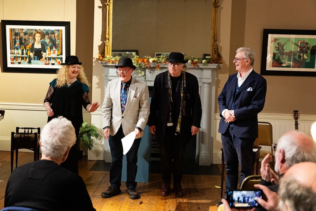 4 people standing in front of a fireplace performing to an audience