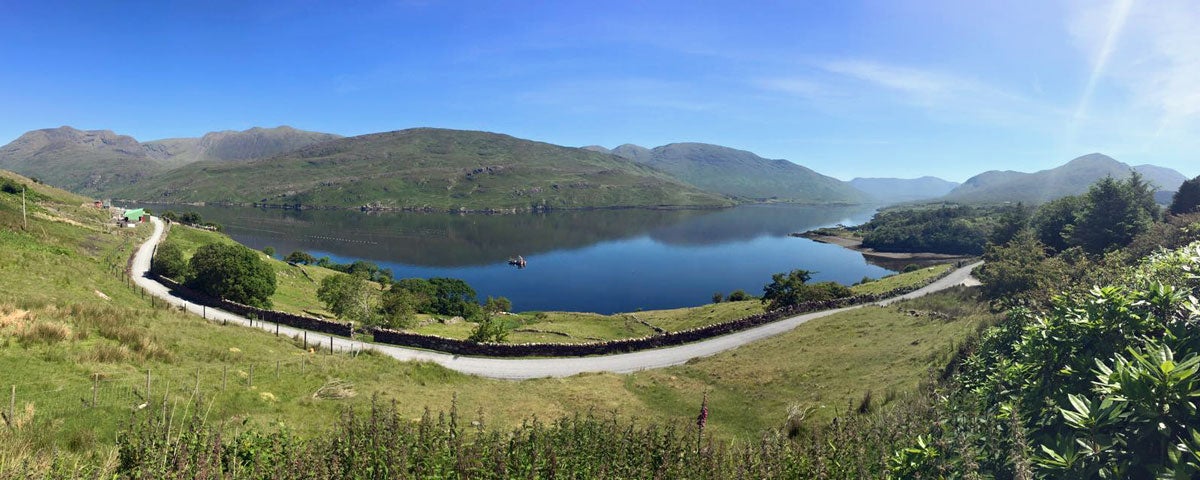 A view of killary fjord with mountains in background and green fields in the foreground