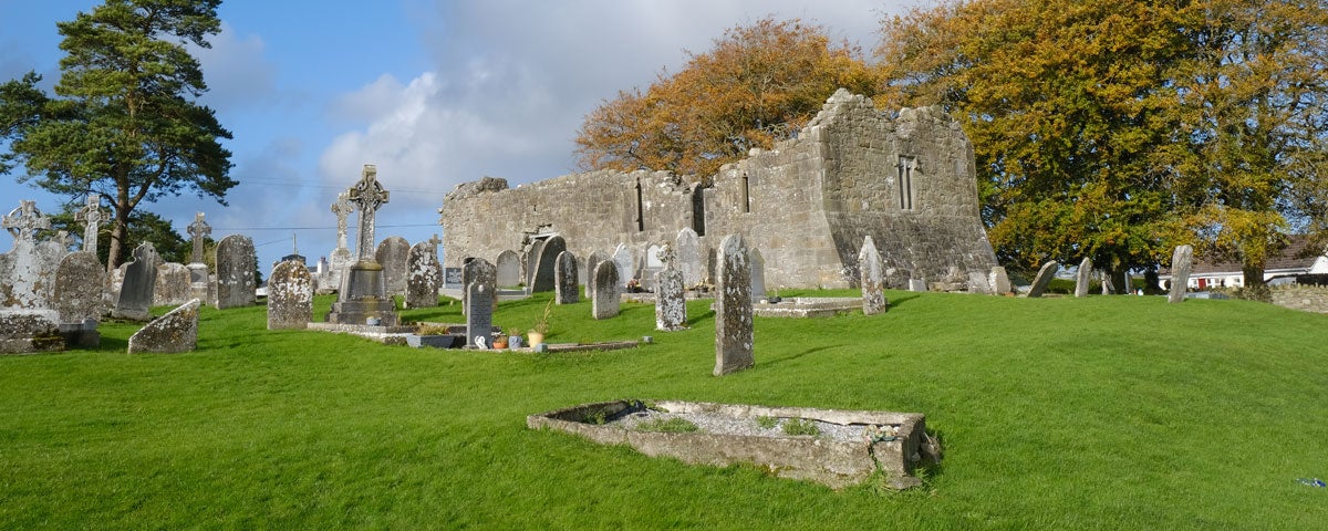 The ruins of a church with some ancient headstones scattered amongst green grass
