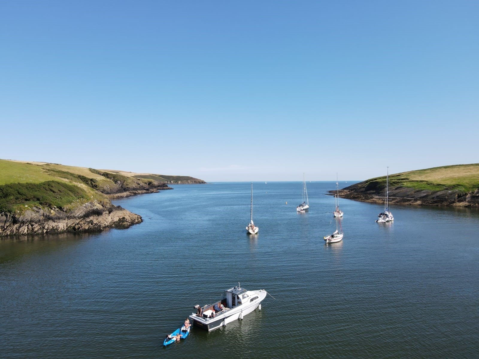 Boats sailing out for the harbour with green land either size