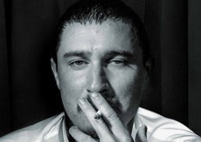 Comedian and actor Tom Rosenthal - headshot of man with half closed eyes and a cigarette up to his mouth