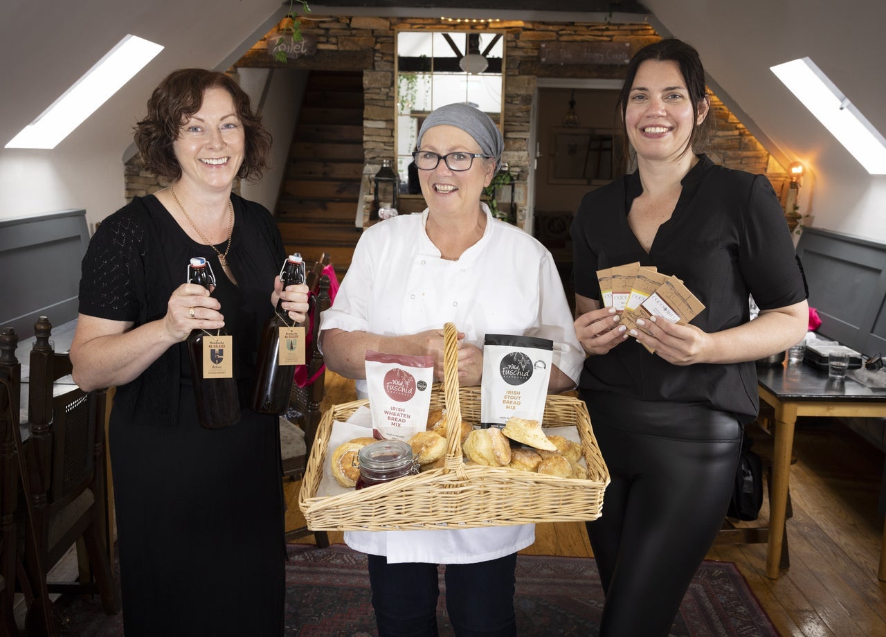 Three ladies standing side by side holding products they have made