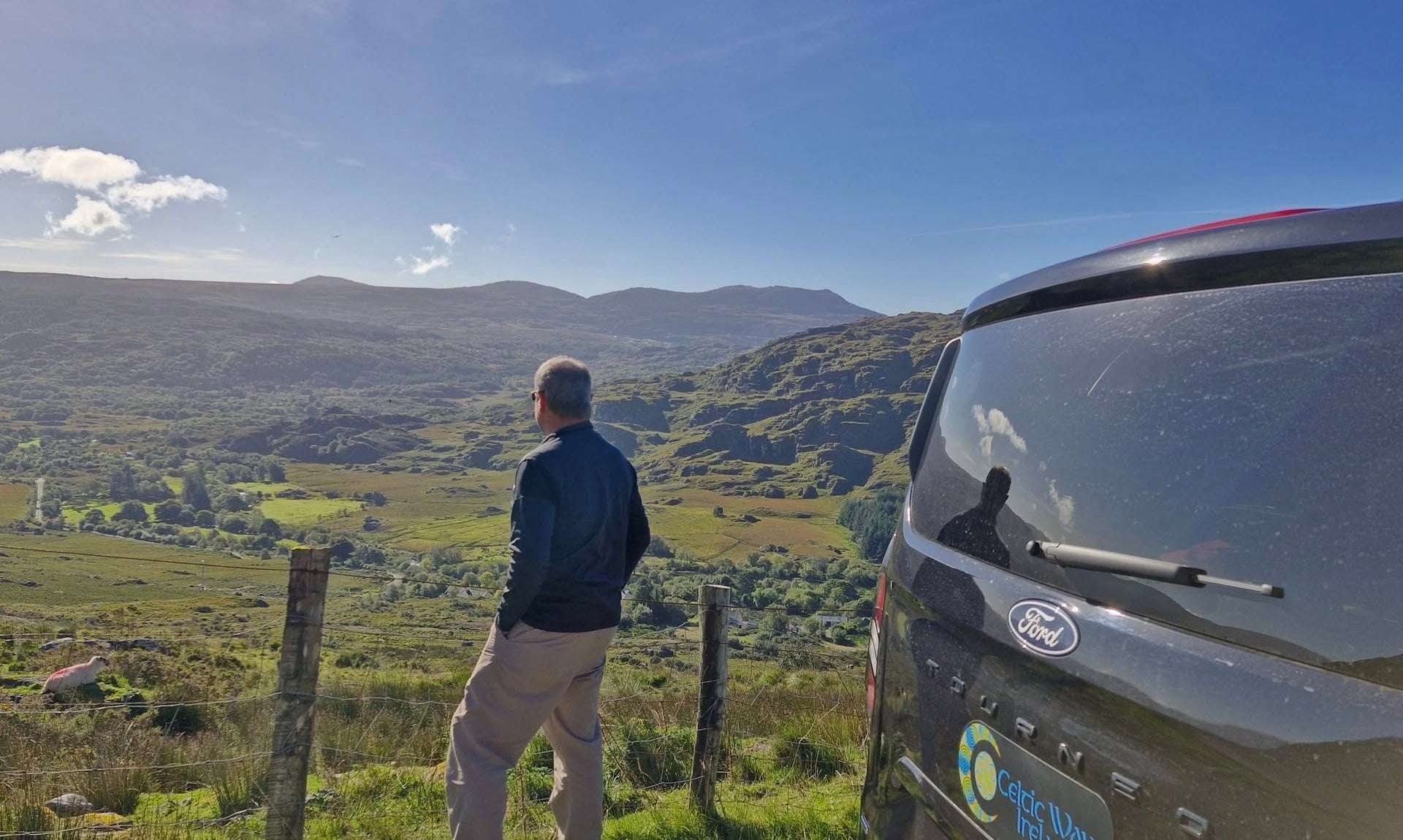 A man looking out over a green valley beside the Celtic Ways Ireland touring mini van