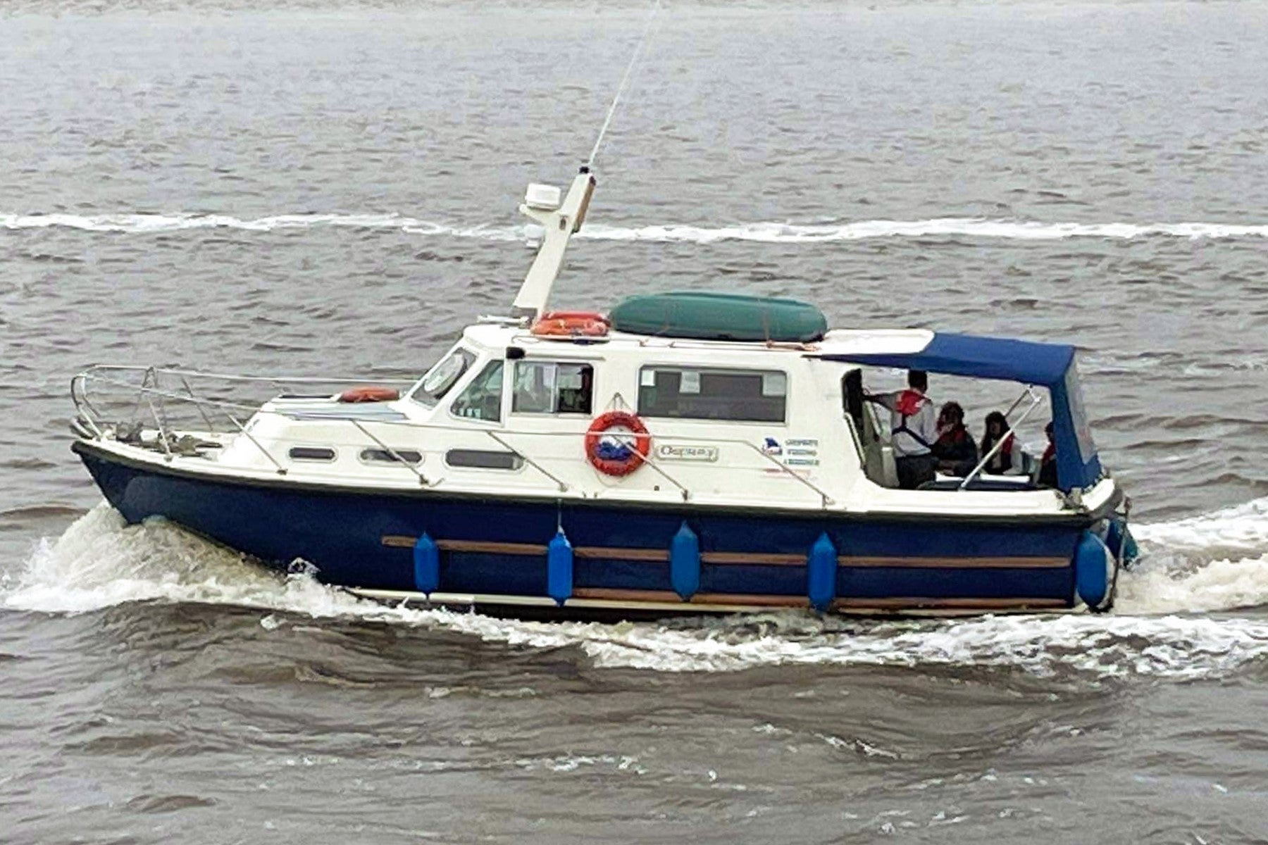Blue and white boat sailing on a grey sea