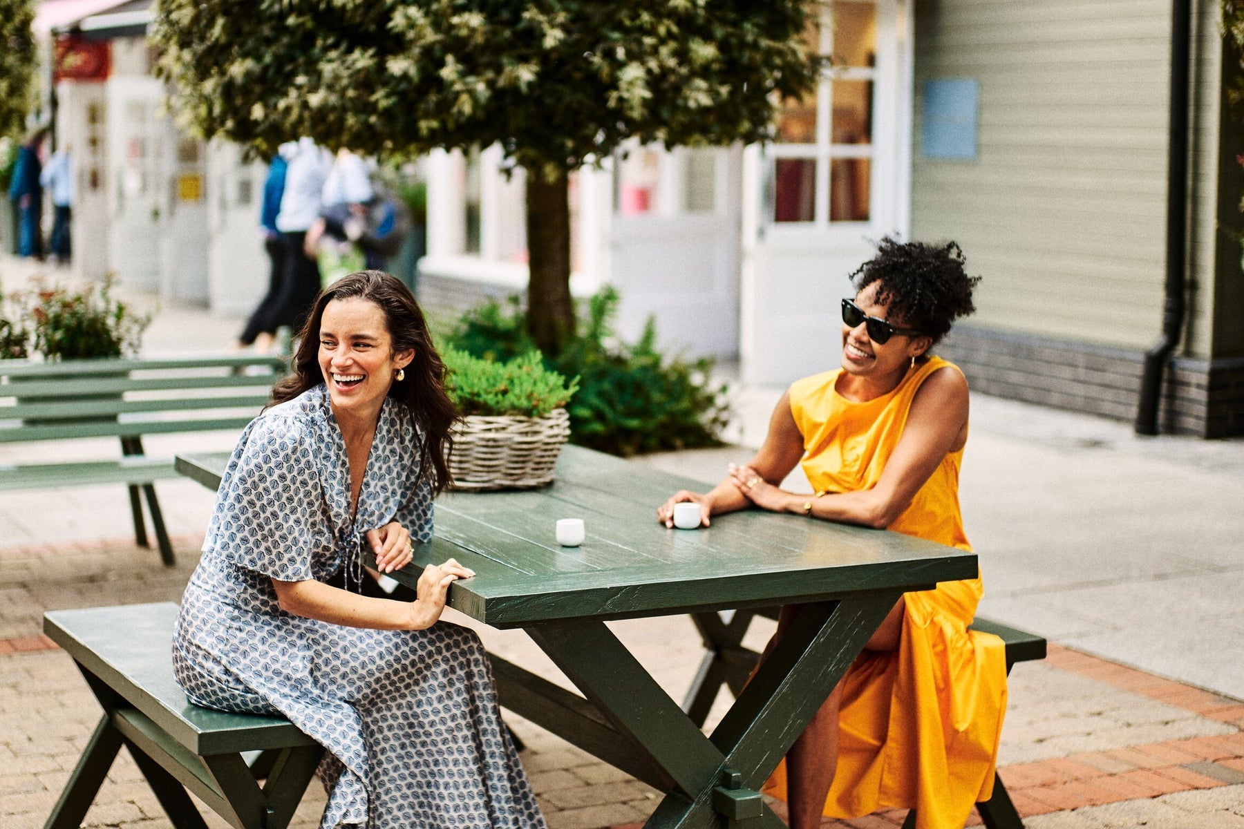 Two ladies smiling and enjoying an espresso outside at a café in Kildare Village