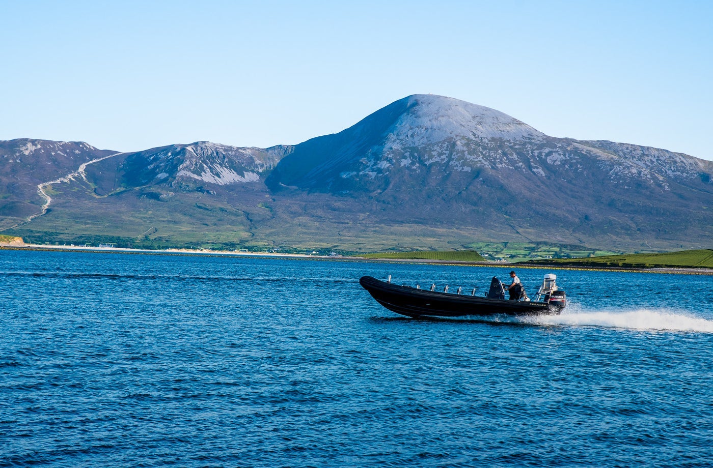A small boat at sea with a mountain in the background