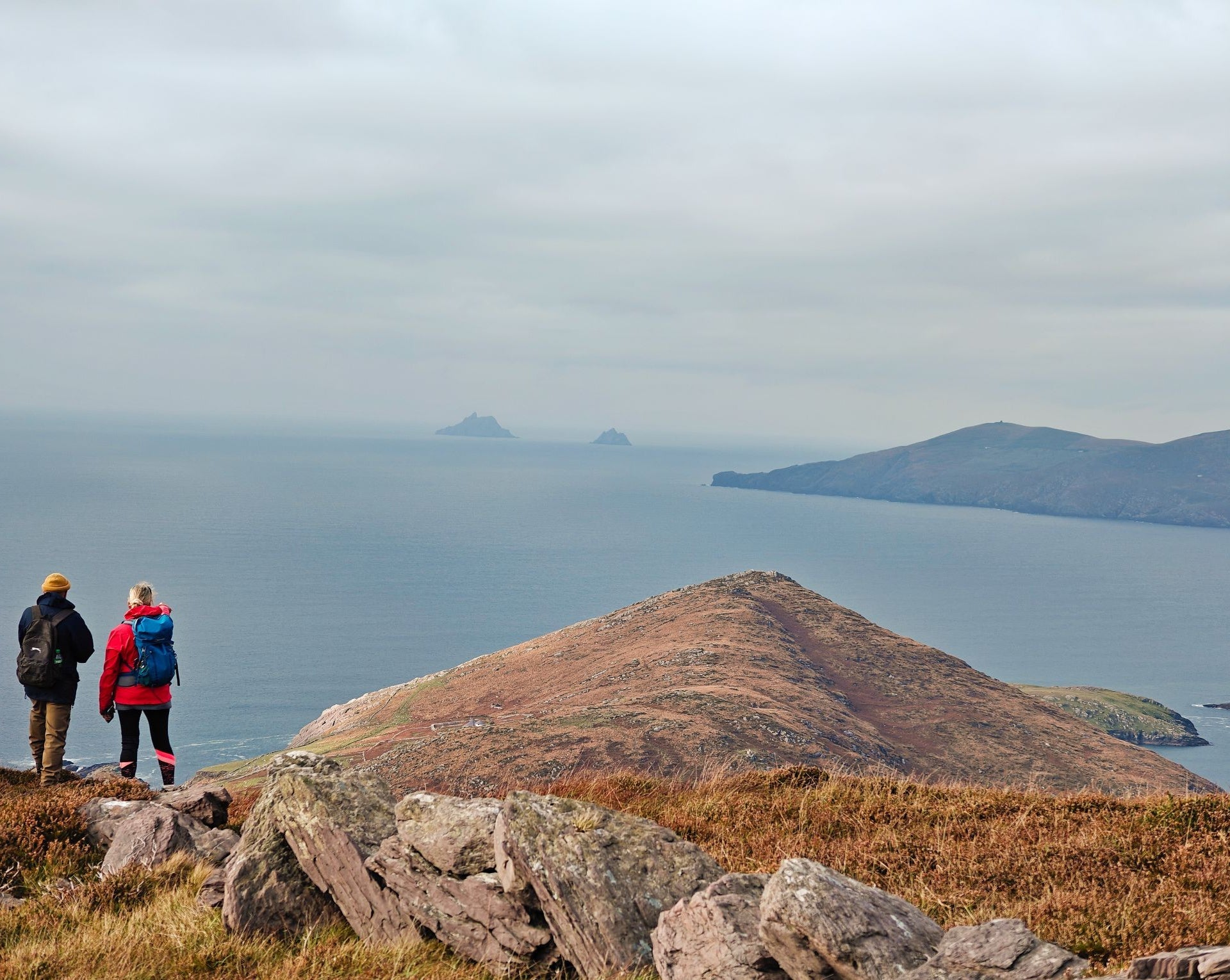 Two people taking a break while out hiking to look out at the sea view and Skellig Rock