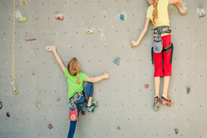 Two children with colourful clothes on a climbing wall