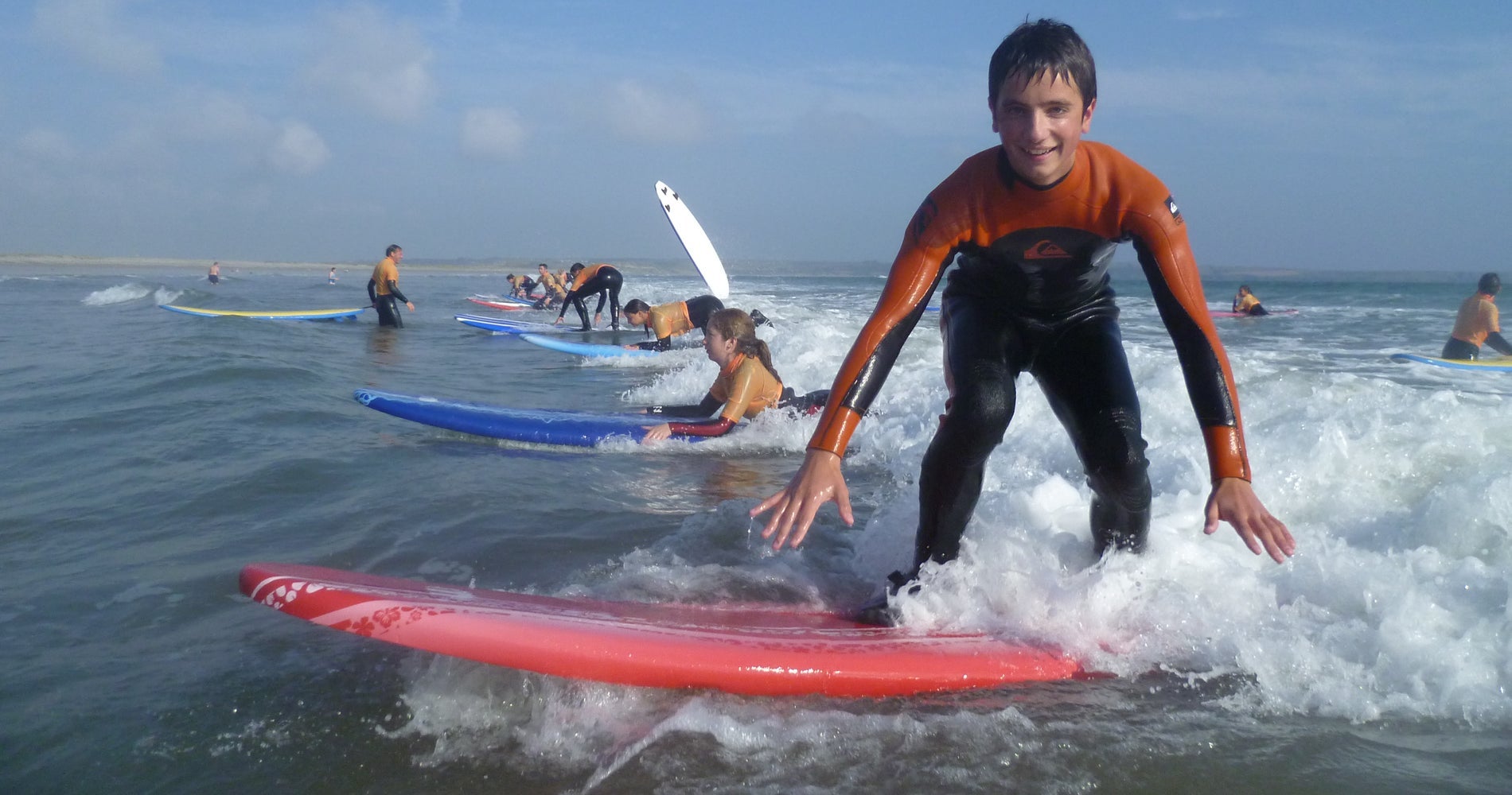 A boy on his surf board during a surf lesson in the sea with Freedom Surf School