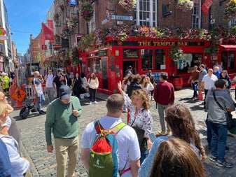 People gather in the sunshine on the street outside the Temple Bar pub in Dublin