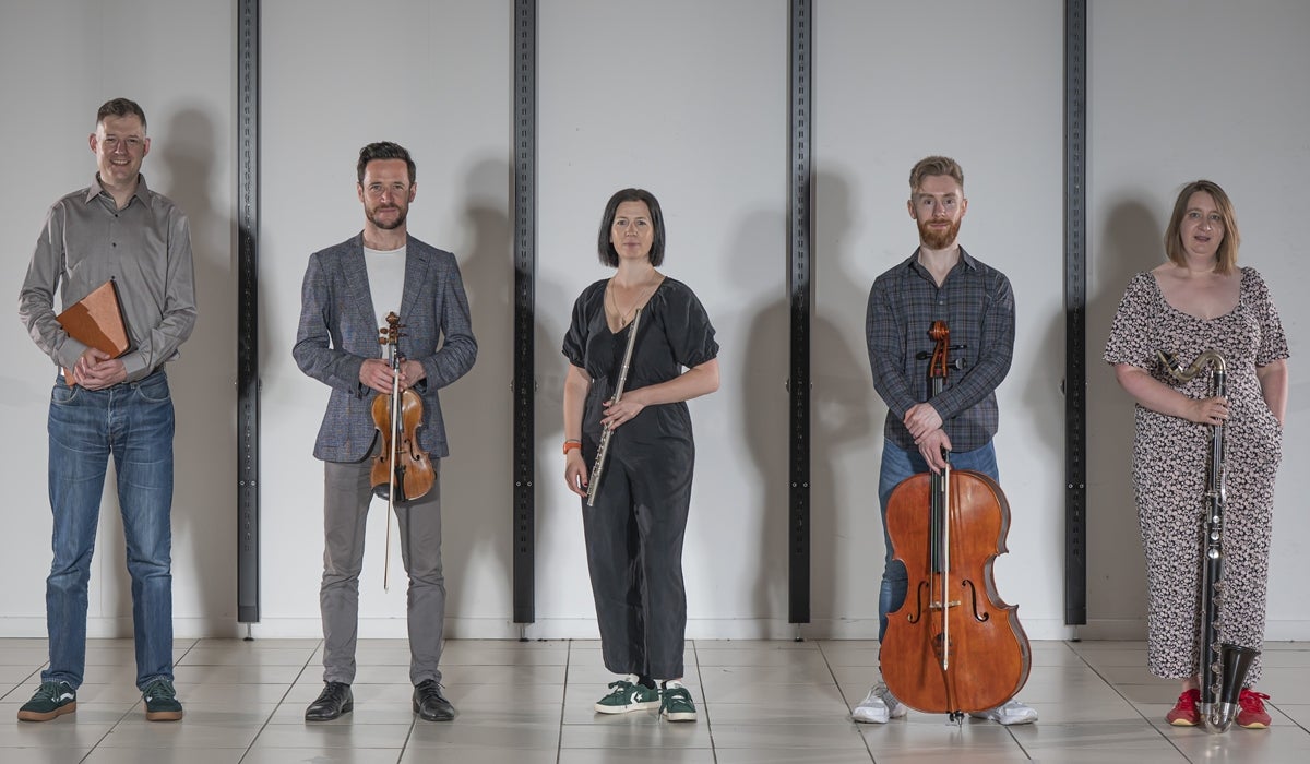 A line of 5 musicians with their instruments, standing slightly apart.