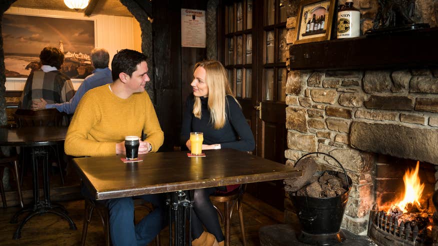 A couple having a drink in front of the fire in the Singing Pub in County Donegal