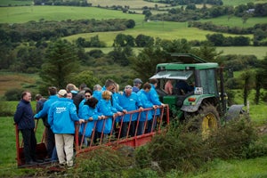 A tour group standing on trailer with a tractor as they enjoy a West Cork Farm Tour.