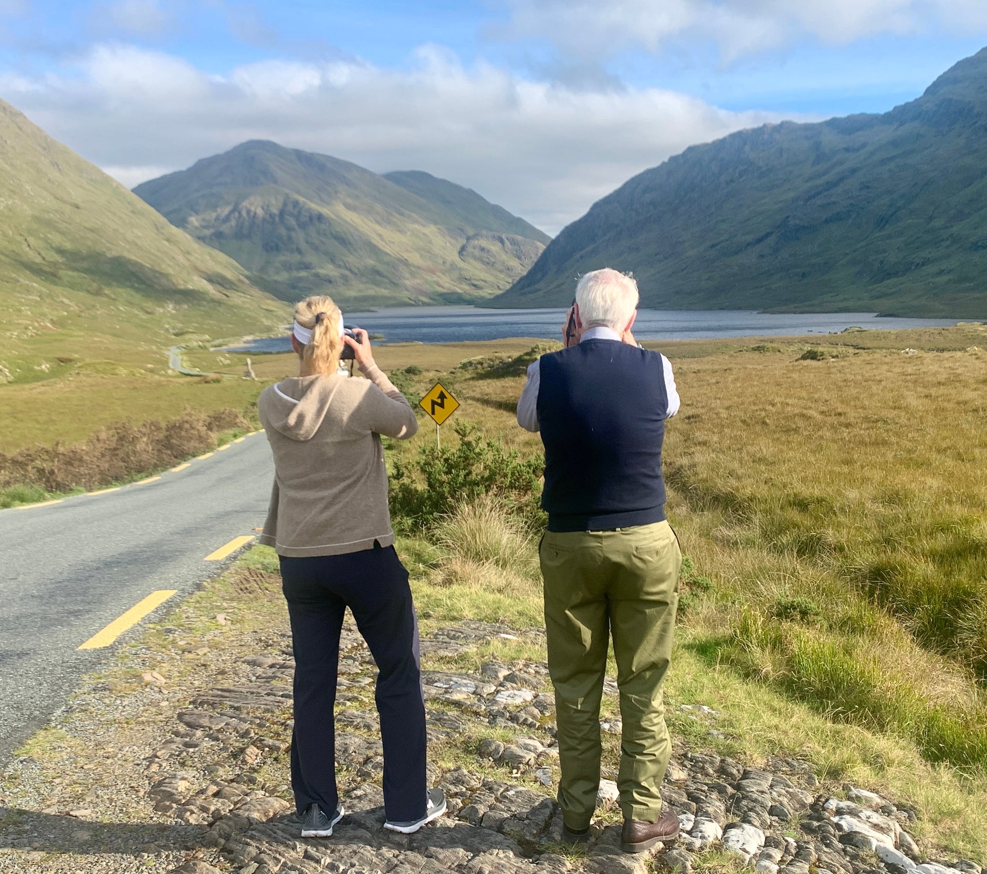Two people taking photos of a lake