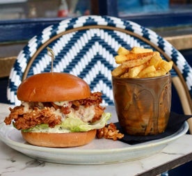 Crispy chicken burger served with lettuce and chips on a plate in an outdoor dining setting