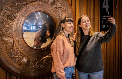 Two ladies taking a photograph at the copper wall mirror at the Abbey Theatre