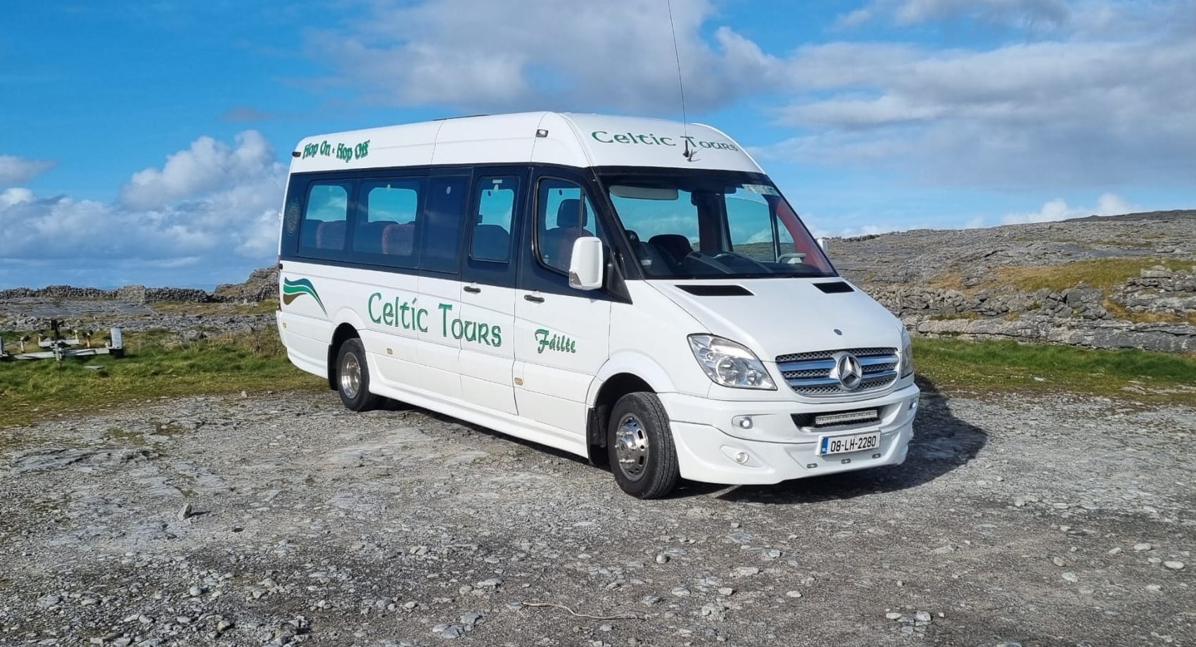 A white mini bus with green logo saying Celtic Tours on the side
