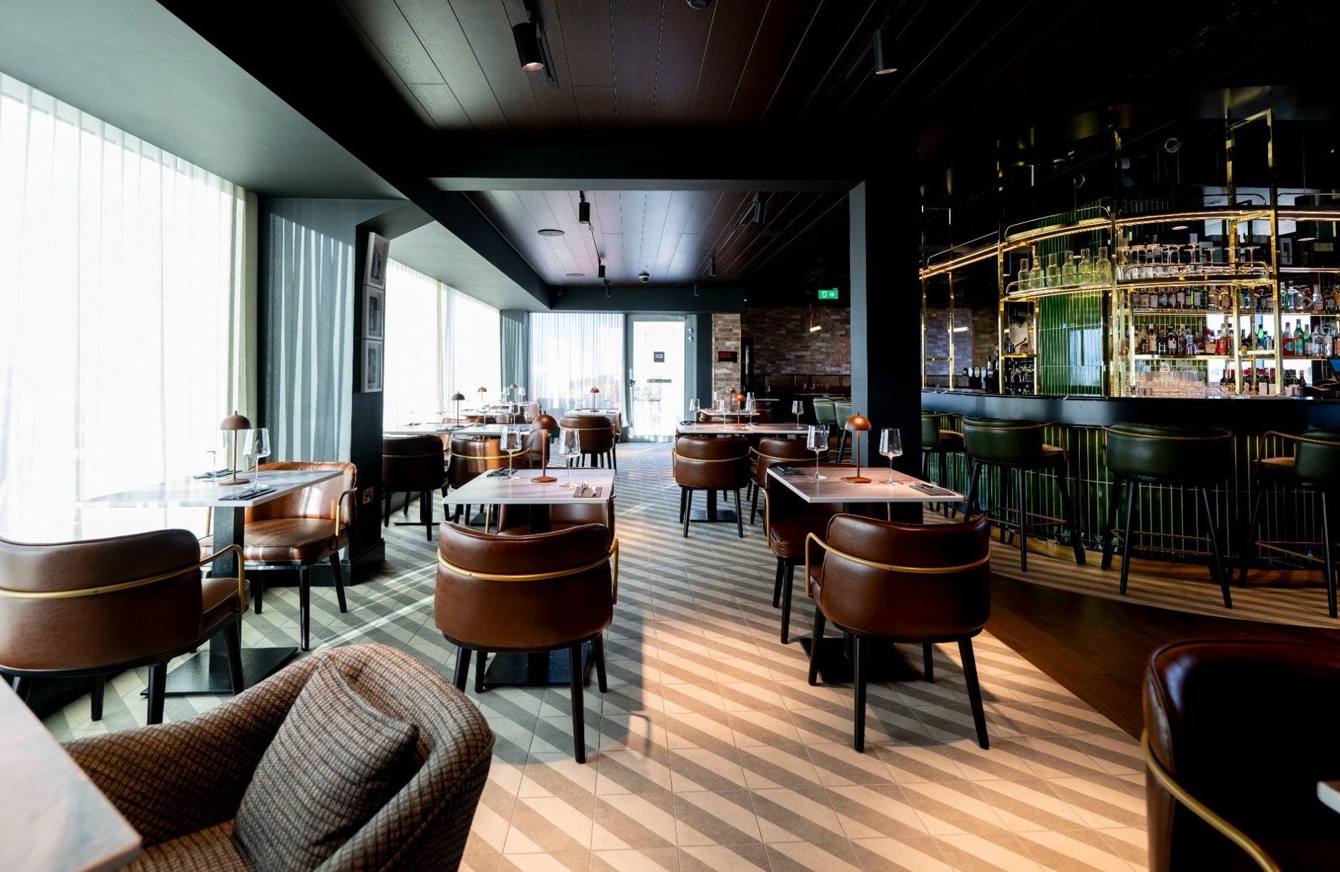 A bar and restaurant painted in dark colours with brown leather seating and floor tones