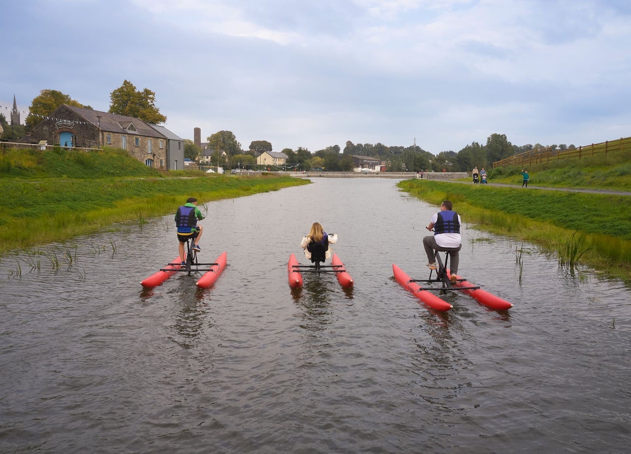 Three people cycling water bikes on a canal